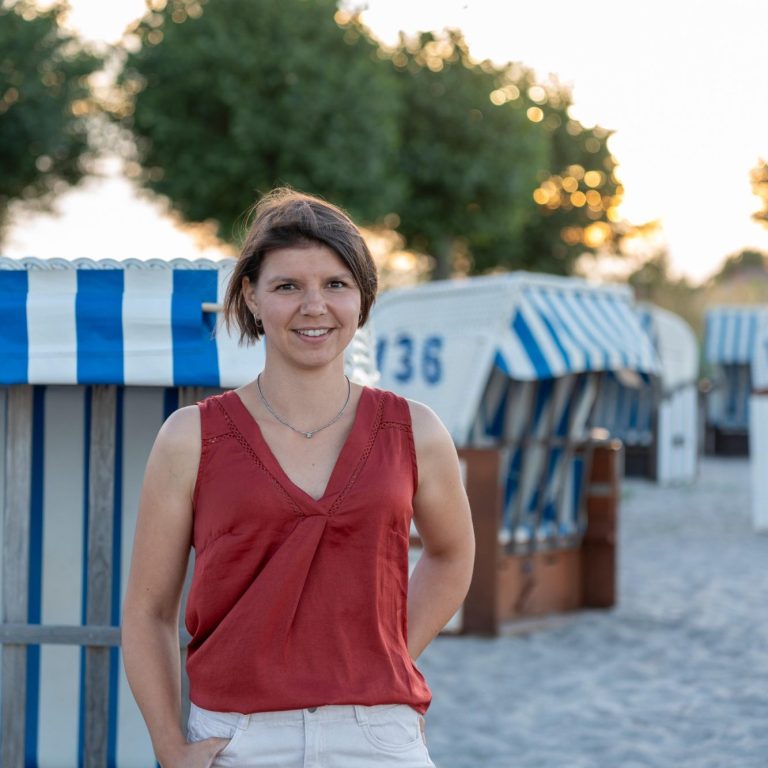 SophieRödiger_Strandkorb(1) Sophie Rödiger am Strand, im Hintergrund mehrere Strandkörbe